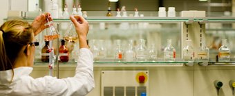 Symbolfoto: Wissenschaftliche Mitarbeiterin in einem Labor prüft den Inhalt von Reagenzgläsern.