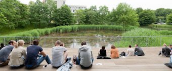 Symbolfoto: Studierende sitzen in der Pause an einem Teich.