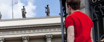 Symbolfoto: Studierender blickt auf das Hauptgebäude einer Universität.