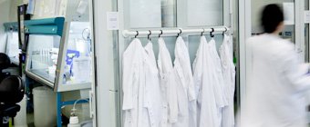 Symbolfoto: Weiße Kittel an Haken im Labor.