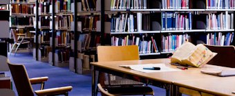 Symbolfoto: Tisch mit aufgeschlagenen Büchern in einer Bibliothek.