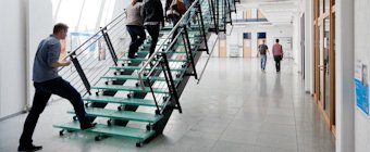 Symbolfoto: Mann steigt die Treppe in der Eingangshalle einer Hochschule hinauf.