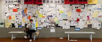 Symbolfoto: Studierende sitzt vor dem Schwarzen Brett der Studienberatung